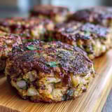 Thick, pan-fried Black-Eyed Pea Burger Patties sizzling in a cast-iron skillet with olive oil, creating a crispy, caramelized exterior.