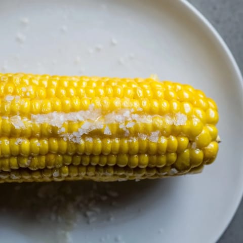Steaming-hot corn on the cob glistening with butter, a simple yet satisfying summer side.