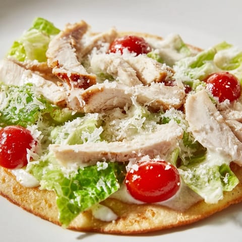 Caesar Chicken Flatbread showcasing golden, crispy edges with juicy grilled chicken slices nestled atop fresh, vibrant romaine lettuce.