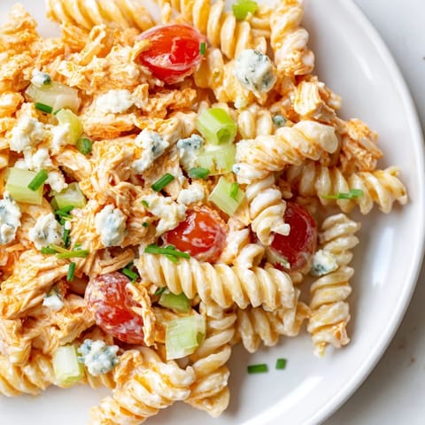 Creamy Buffalo Chicken Pasta Salad served chilled, garnished with crumbled blue cheese and chives, perfect for a summer picnic or potluck side dish.