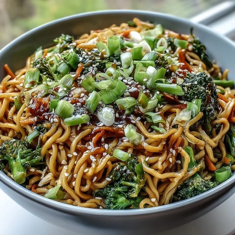 Freshly cooked Asian Teriyaki Noodle Bowl in a white bowl, featuring glossy egg noodles tossed with vibrant broccoli, carrots, and green onions.