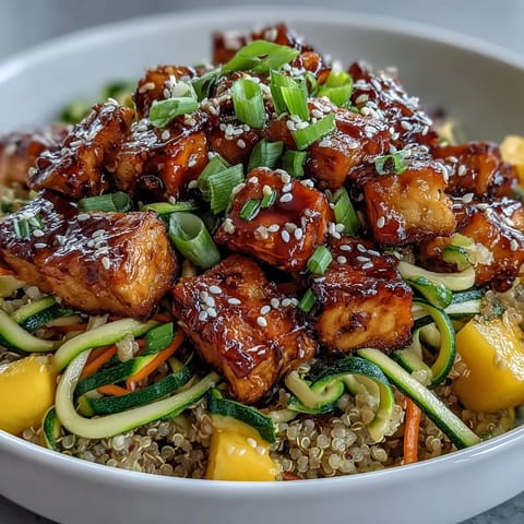 Crispy baked tofu pieces and spiralized zucchini and carrots sit atop fluffy quinoa, drizzled with glossy teriyaki sauce.