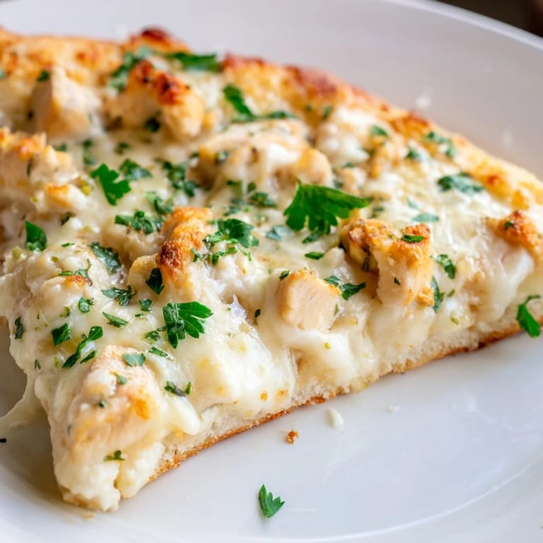 Sliced Chicken Alfredo Pizza on a wooden board, showing the crisp crust and red onion garnish, ready for a family dinner.  