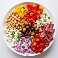 A vibrant bowl of Crunchy Antipasto Chopped Salad with chickpeas, salami, mozzarella, and colorful crisp vegetables tossed in zesty Italian dressing.  